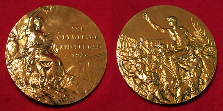 Złoty medal olimpijski z 1928 roku.
Awers to Nike z gałązką oliwną, datą i miejscem wydarzenia oraz Akropolem w tle. Rewers przedstawia tłum niosący zwycięzcę jeden z konkurencji sportowych na olimpiadzie.